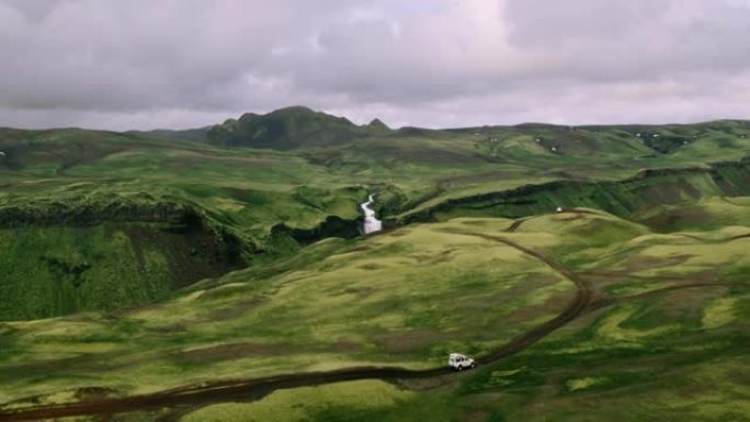 背景为瀑布的4x4 SUV汽车在山路上行驶的空中拍摄