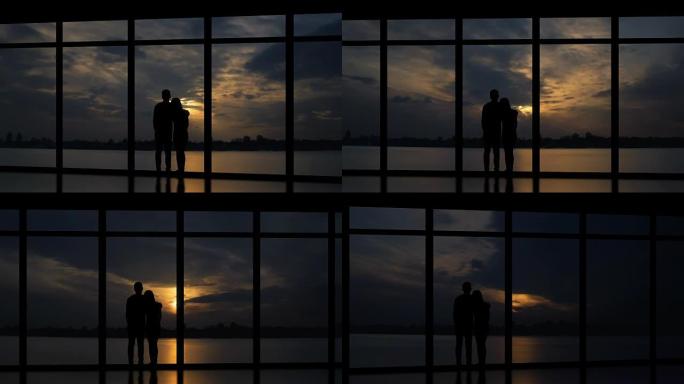 男人和女人站在日落背景上的窗户附近。时间流逝