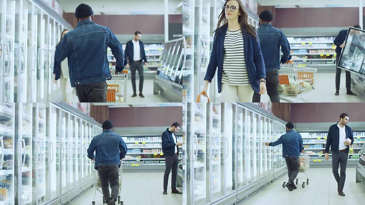 在超市: 快乐时尚的家伙推购物车，在商店的冷冻商品区选择产品。带玻璃门冰箱的大购物中心。