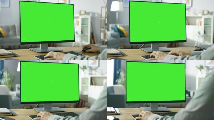 在专业自由职业者的肩膀上，在家中使用绿色模型屏幕个人计算机。男人的手打字，他在舒适的客厅中浏览互联网