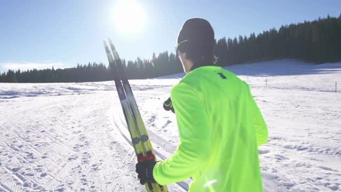年轻的男子越野滑雪运动员，背着滑雪板