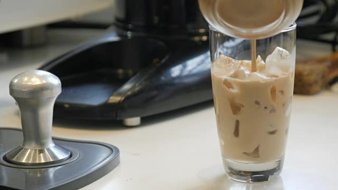 咖啡师将新鲜咖啡倒入一杯冰中