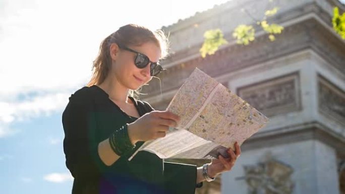女游客站在巴黎凯旋门前，看着城市地图