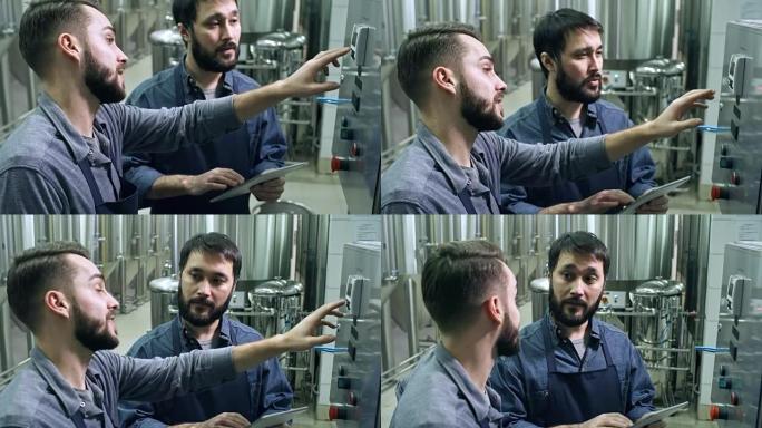 啤酒厂工人向同事解释如何操作机器
