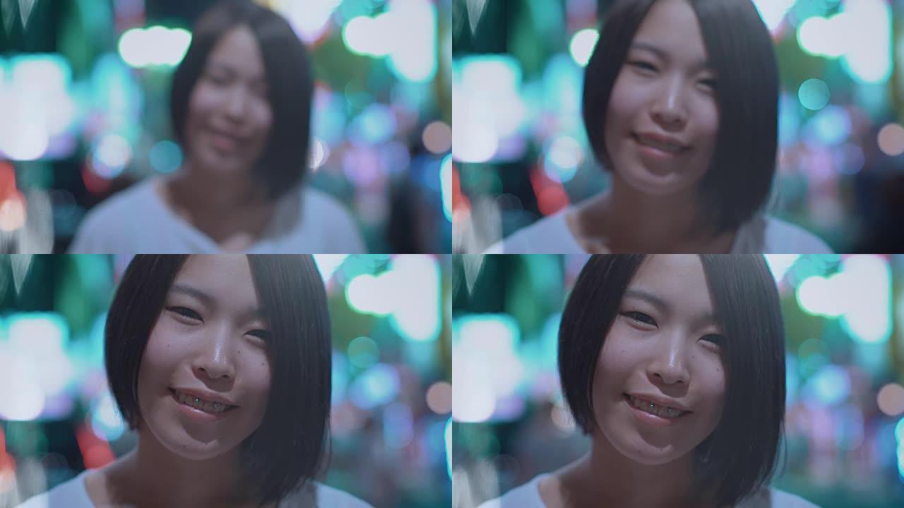 来聚焦镜头前微笑的美丽另类东亚女孩的肖像。背景中模糊的大城市灯光发光。