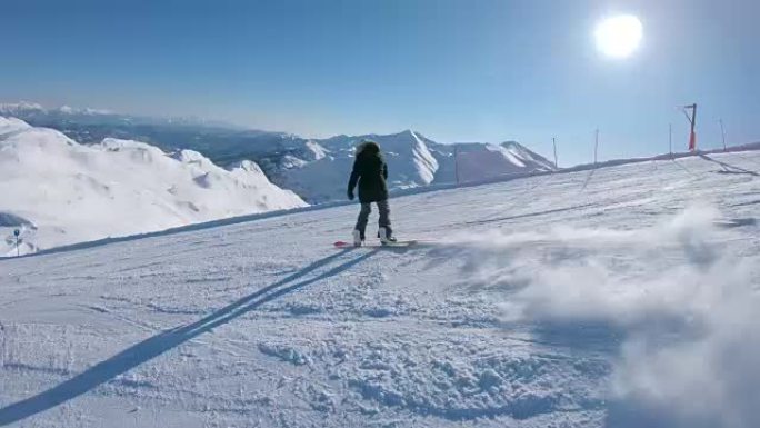 跟随: 灿烂的冬日阳光照在空旷的斜坡上的女子滑雪板上。
