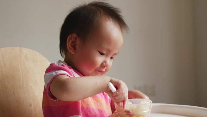 可爱小女孩学用勺子自己吃饭吃面条