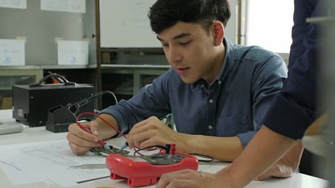 亚洲学生正在教室里与老师一起学习电子学并测量电路中的信号。
