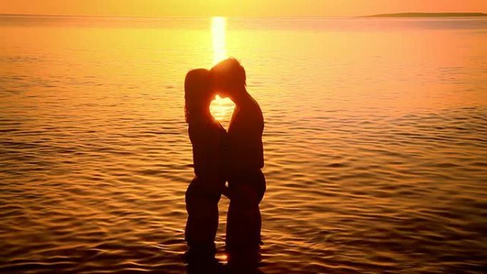 高清：一对情侣在日落时接吻的剪影