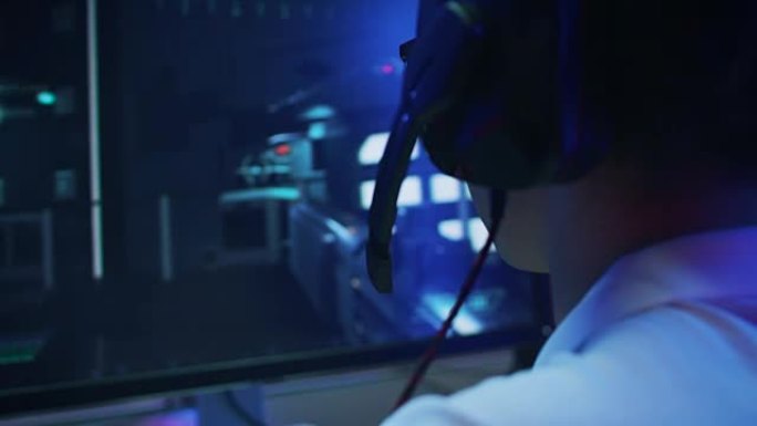 职业玩家在个人电脑上玩第一人称射击游戏在线视频游戏的特写镜头。他正在通过耳机与他的团队交谈。复古拱廊