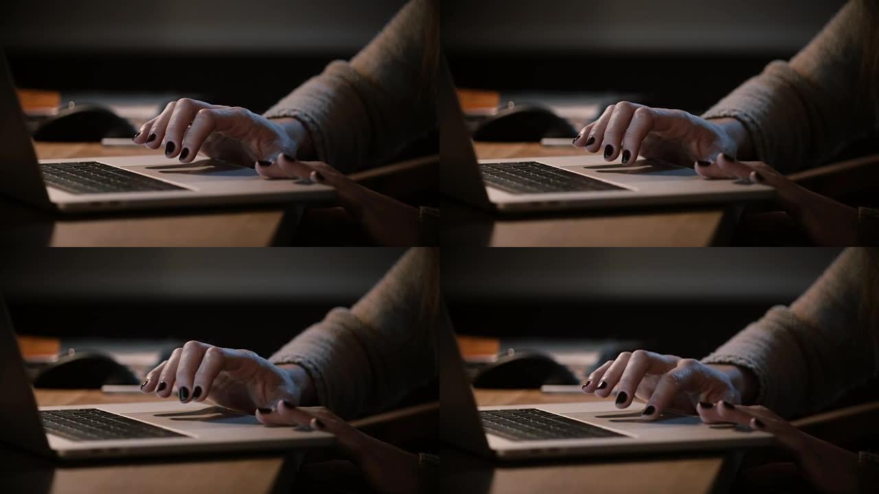 女孩在晚上使用笔记本电脑触控板和触摸板。特写。女性手放在电脑触摸板上。在家工作到很晚。4K