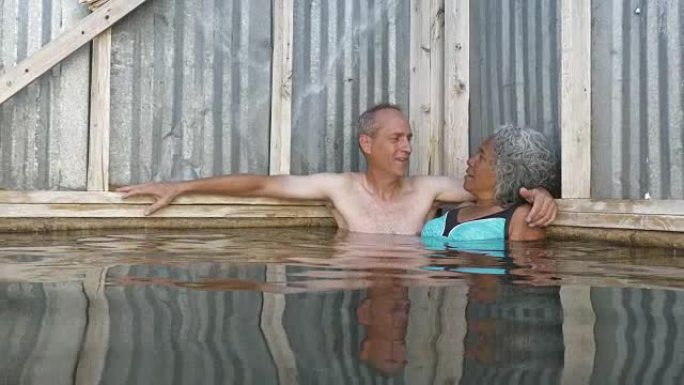 混合种族的高级夫妇享受热水游泳池