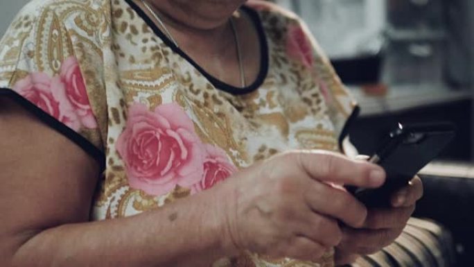 老年亚洲妇女在家中使用智能手机