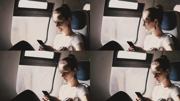 年轻美丽的白人妇女使用智能手机坐在火车靠窗的座位上，在上班途中在应用程序上键入消息