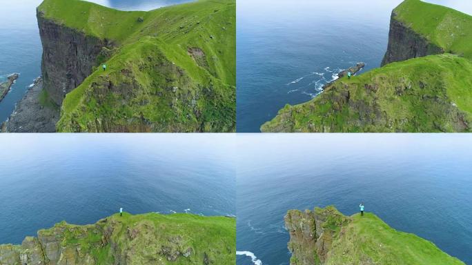 空中: 在高高的岩石悬崖上飞行，女人站在草地上。