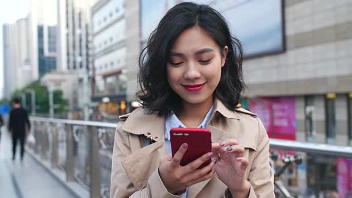 一位年轻的年轻亚洲妇女在城市使用手机