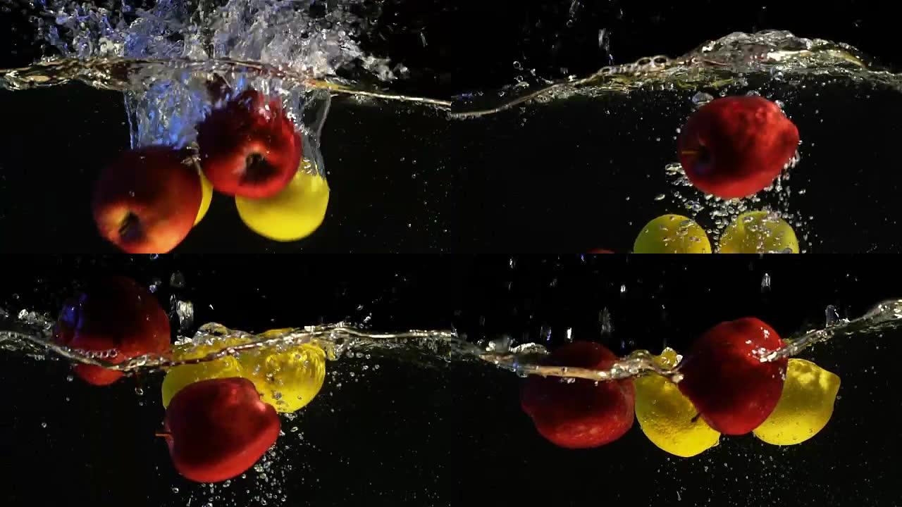 黄色柠檬和红苹果落入水中气泡的慢动作视频。孤立的黑色背景上的水果。