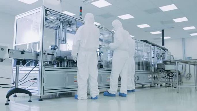 在制造工厂团队的科学家穿着无菌防护服设置/程序现代工业3D打印机，高精度制造过程中的半导体。