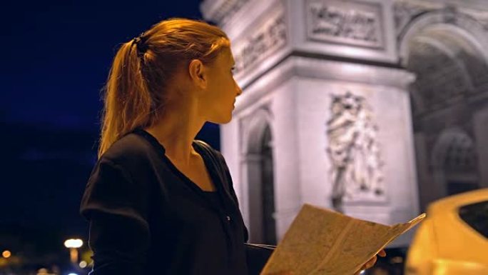 带有巴黎城市地图的游客在夜间欣赏凯旋门纪念碑