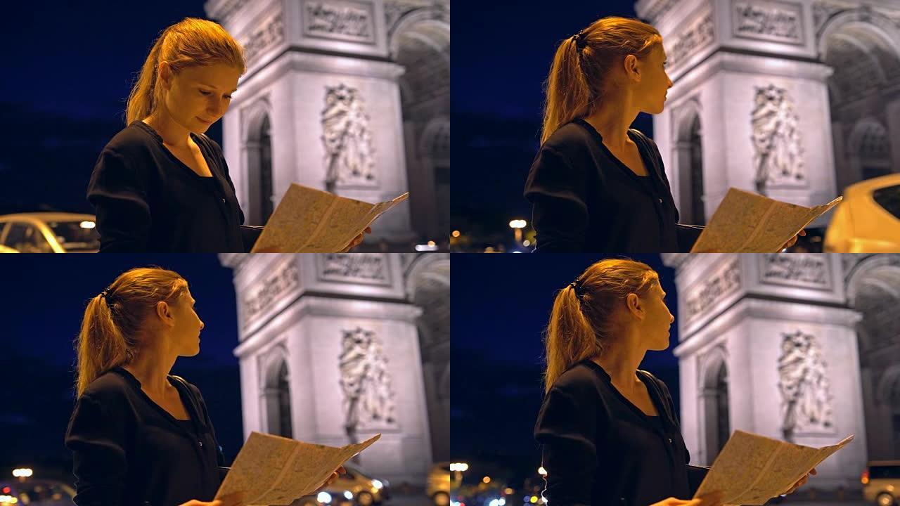 带有巴黎城市地图的游客在夜间欣赏凯旋门纪念碑