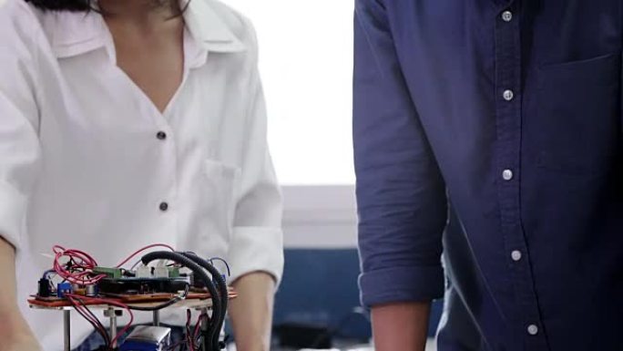 青少年为他的学校机器人俱乐部项目在一个功能齐全的可编程机器人上工作。创意设计师在车间测试机器人原型。