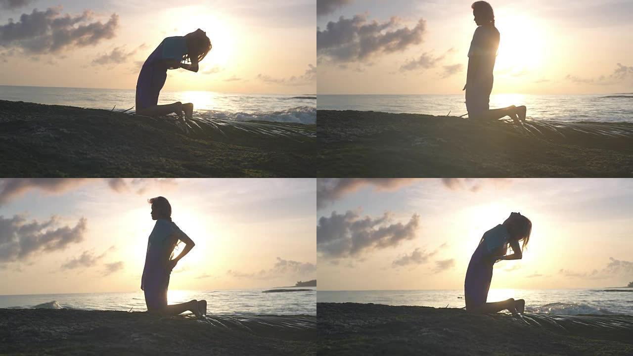 海滩上的瑜伽。以骆驼姿势冥想的女人。日落