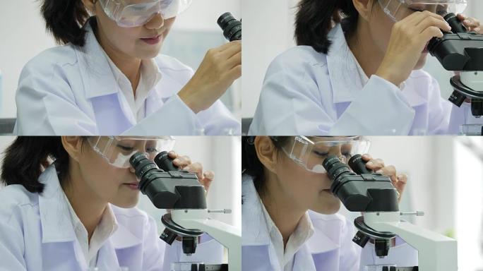 在实验室里通过显微镜观察的亚洲女性医学研究科学家