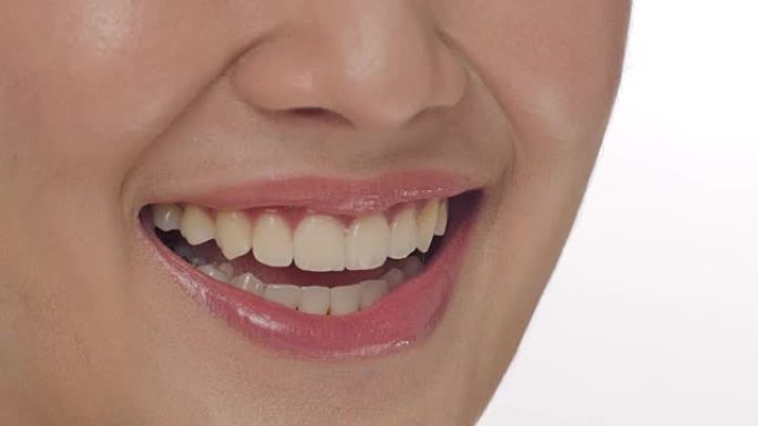 一个女人在白色背景下用牙齿微笑的特写镜头