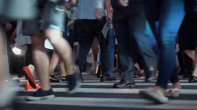 在大城市里，一群行人/穿过人行横道的人。专注于腿。