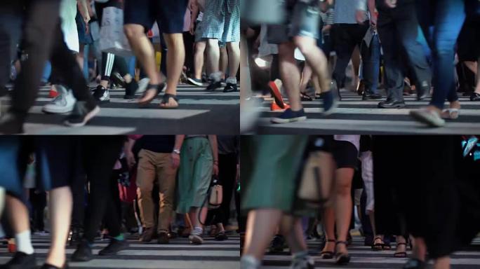在大城市里，一群行人/穿过人行横道的人。专注于腿。