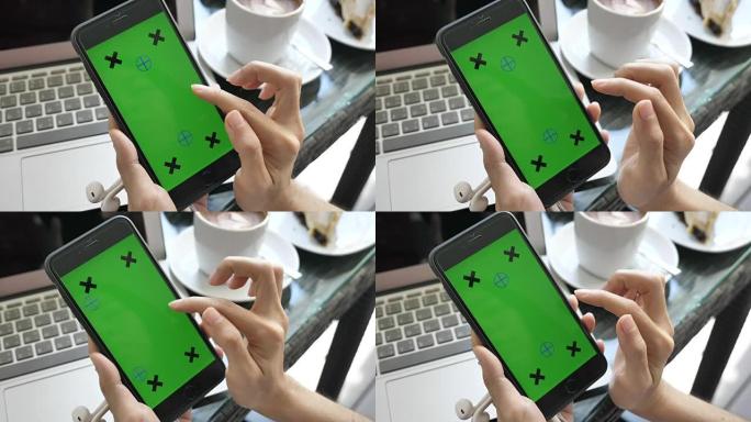 女性在咖啡厅使用带有绿屏的手机，色键