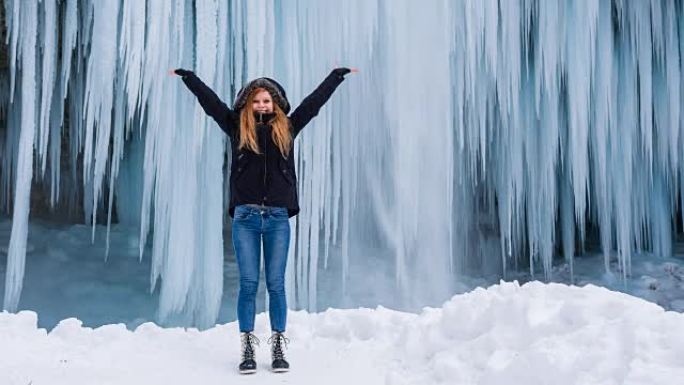 年轻女子在令人叹为观止的冬季景观前伸出双臂