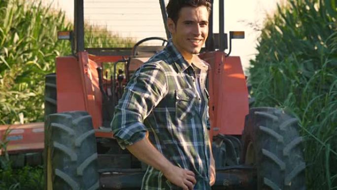 一位美丽的年轻农民 (学生) 的肖像在拖拉机的田间工作，成功的微笑，快乐，穿着衬衫，玉米田。