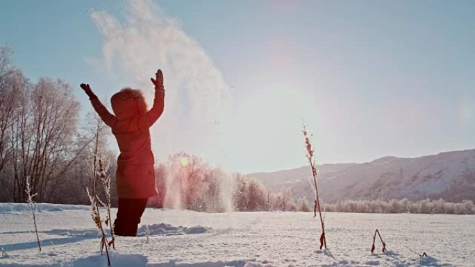 SLO MO女人在美丽的晴天向头顶扔雪