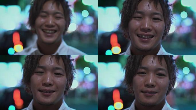 来聚焦年轻英俊的日本小伙子微笑和大笑的肖像。背景中模糊的大城市灯光发光。