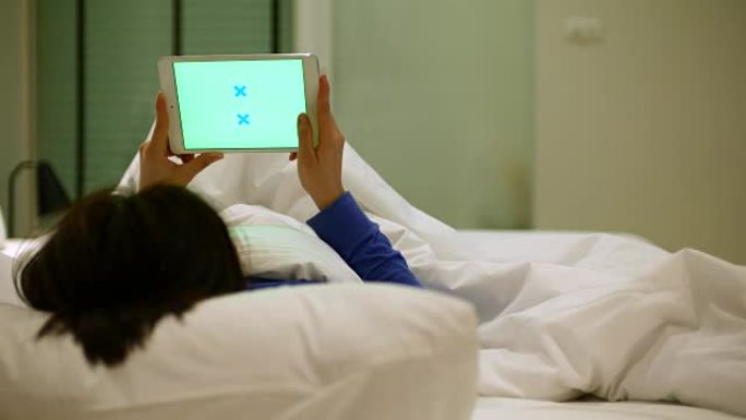 使用数字平板电脑在床上绿屏的年轻女子，4K(UHD)