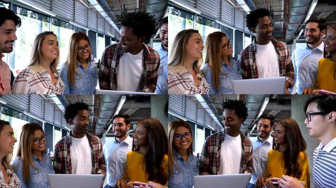 热情的黑人笑着拿着笔记本电脑，他的团队在讲话时都在注意