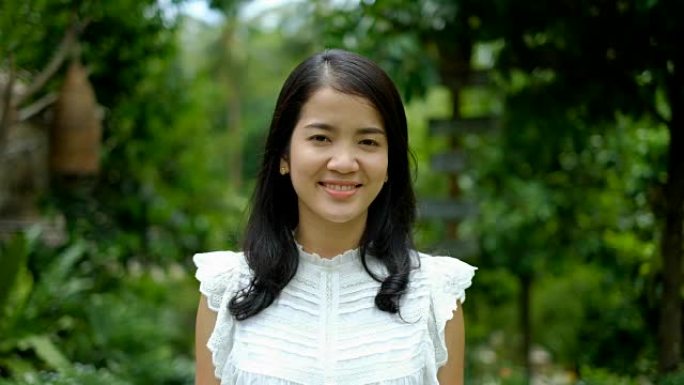 穿着白色西装的快乐年轻亚洲女子在绿色自然背景下微笑和大笑