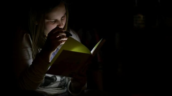 十几岁的女孩用手电筒看书
