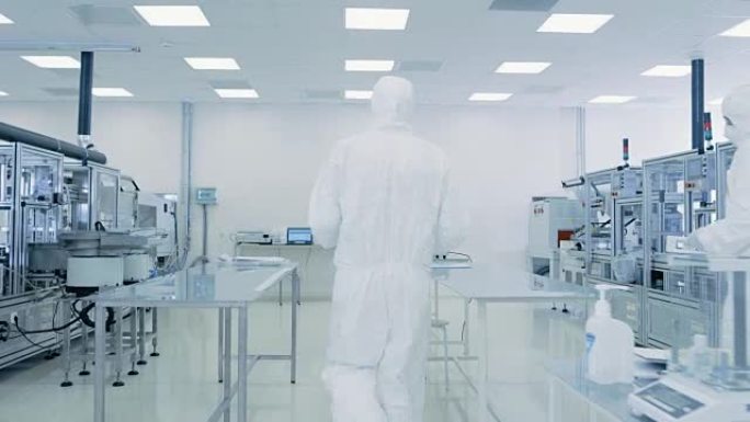 穿着防护服的科学家通过实验室携带成品箱。工厂里有现代工业机械的工人。产品制造过程: 制药、半导体、生