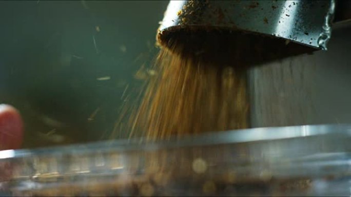 烘焙的咖啡豆落入研磨机咖啡中，它们被压碎以具有完美的尺寸并得到咖啡粉。