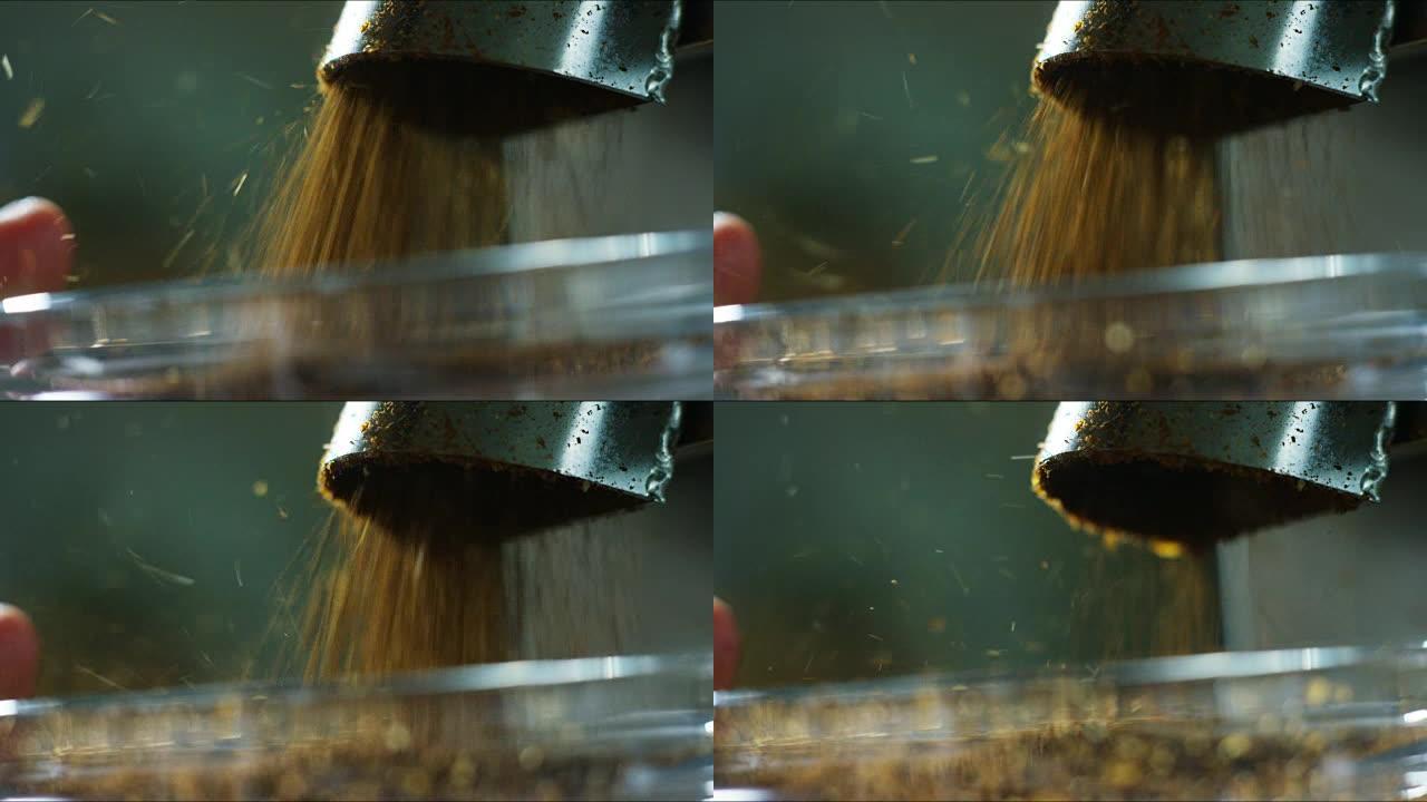 烘焙的咖啡豆落入研磨机咖啡中，它们被压碎以具有完美的尺寸并得到咖啡粉。