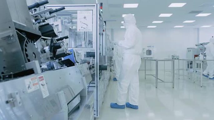 在实验室中，科学家穿着无菌防护服套装的现代工业3D打印机，在加工过程中高精度制造半导体。
