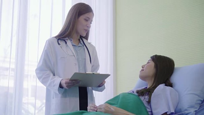 年轻的亚洲医生妇女在剪贴板上显示病床女性患者的信息治疗。医学、年龄、医疗保健和人的概念。