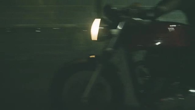 稳定的镜头: 骑自行车的人在黑暗地区骑摩托车
