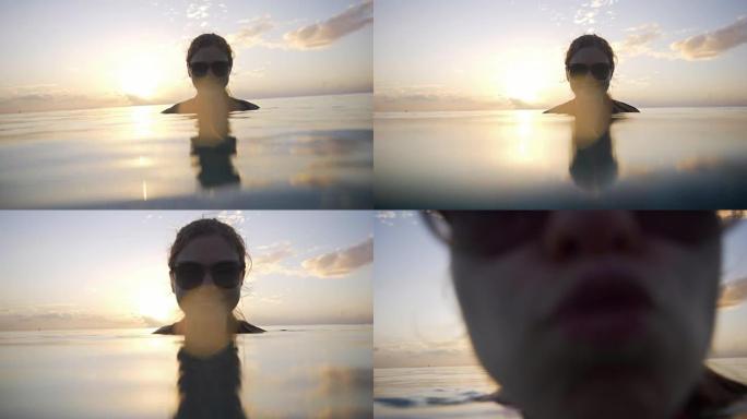 日落时分在海里享受的女人亲吻相机