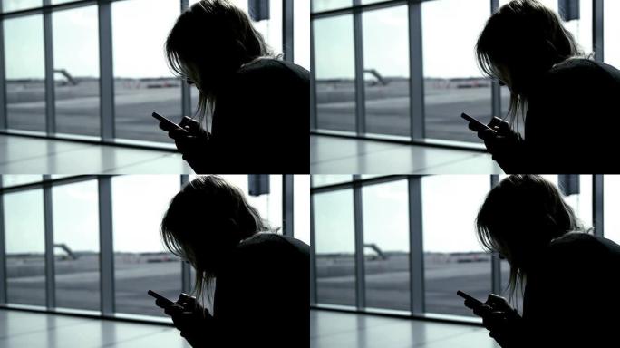 女孩在机场航站楼使用智能手机，等待航班