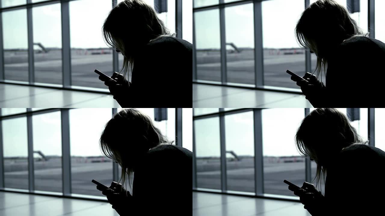 女孩在机场航站楼使用智能手机，等待航班