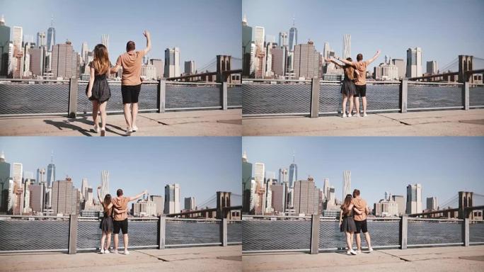 快乐的欧洲游客夫妇举起双手举起手臂，到达令人惊叹的曼哈顿天际线，布鲁克林大桥慢动作