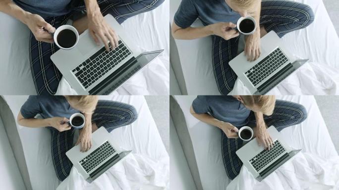 穿着睡衣的男人喝咖啡和使用笔记本电脑